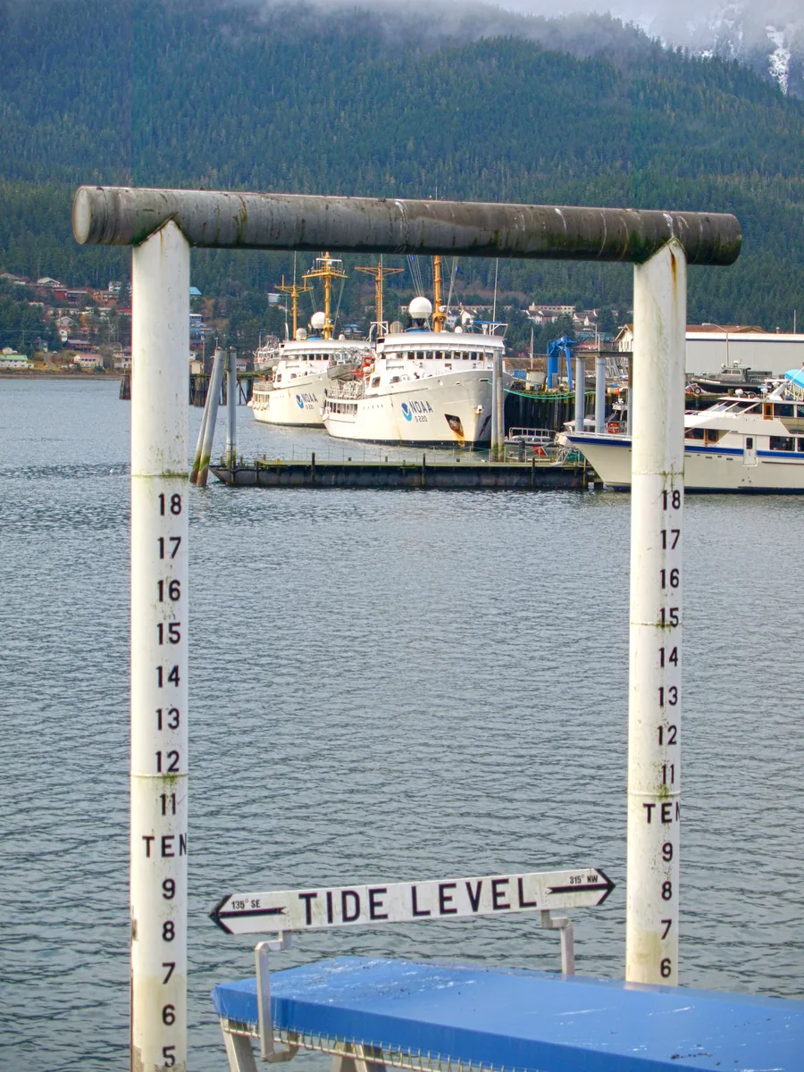 Tide-level staff gauge di dermaga Juneau, Alaska Tenggara, dengan kapal-kapal NOAA bersandar di latar belakang
