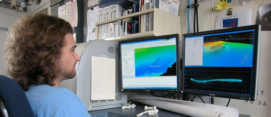 Seorang hidrografer meninjau data sonar multibeam untuk membangun model tiga dimensi dasar laut