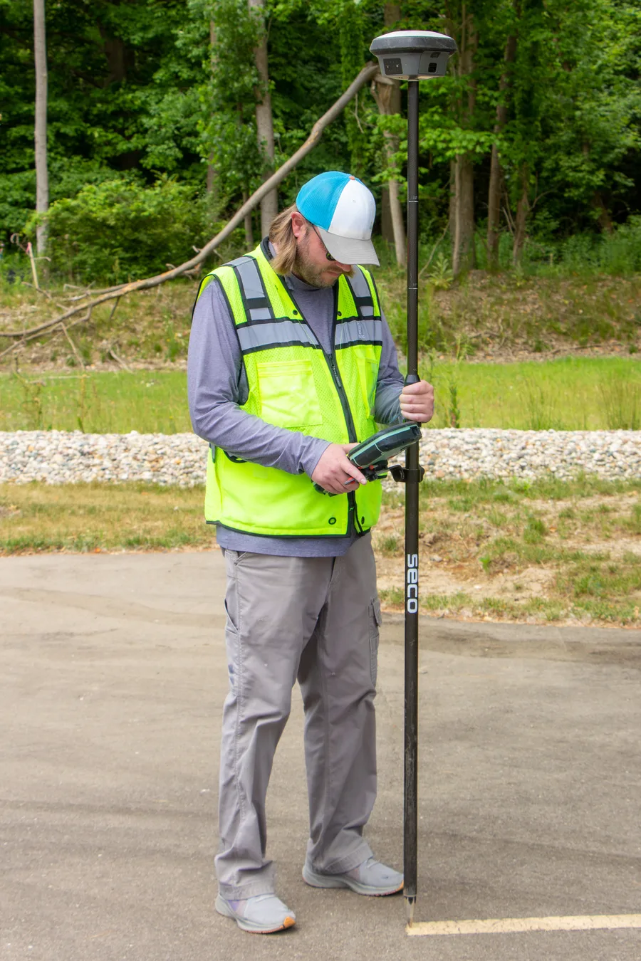Surveyor menggunakan receiver GNSS dengan solusi RTK yang dipasang di atas tongkat